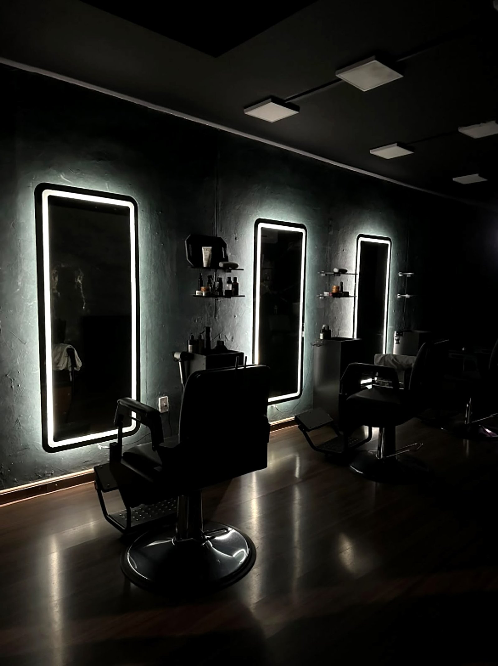 Ambiente climatizado da Santos Barber Studio com espelhos de LED e cadeiras de barbeiro, em Resende, RJ